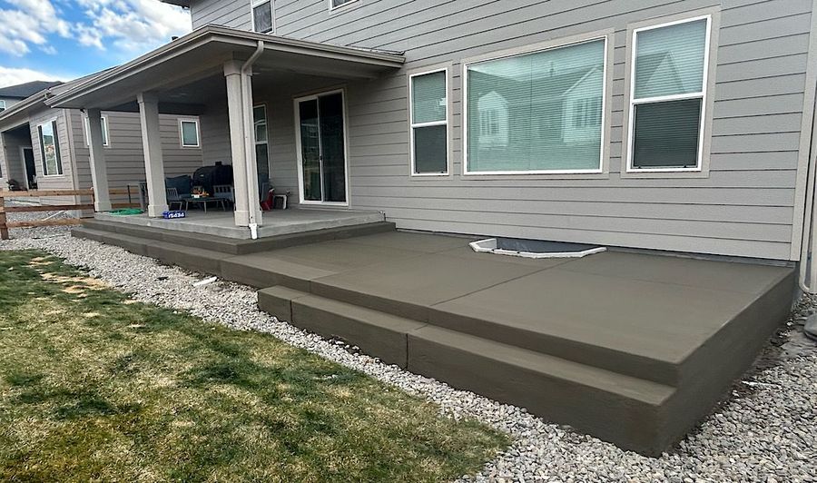 Back patio with a large gray wooden deck beside a house and patio cover
